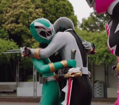 one green ranger hugs another while another looks on