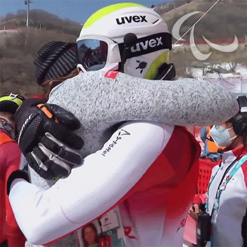 two snow skiers hugging in the midst of competition