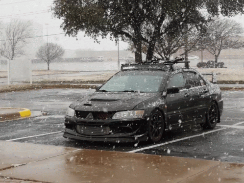a car sits in a parking lot during a snow storm