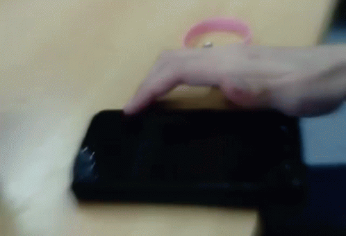 a hand with a purple band is holding onto a cell phone