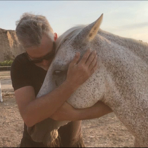 a man holds his face on the nose of a horse