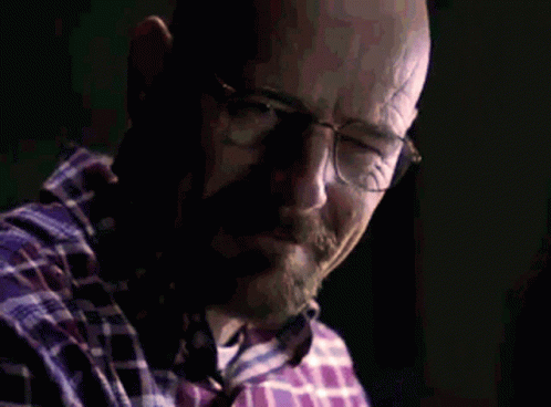 a bald man looking at his cellphone in a dark room