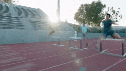 two men jumping over a hurdles in a stadium