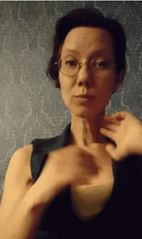 a woman with glasses and arm extended pointing at soing