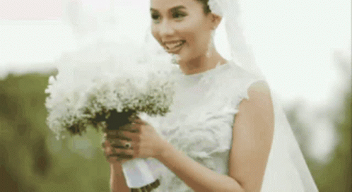 a bride poses while holding flowers in her hands