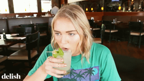 a girl is holding a green beverage and posing for the camera