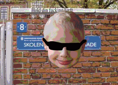 a man with sunglasses on his head is in front of a brick wall