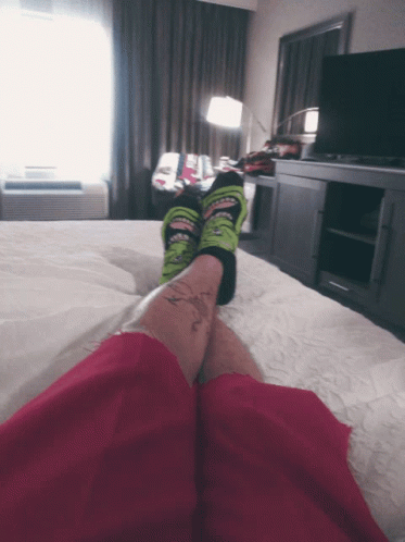 a person with bright colored shoes and blue pants laying on a bed
