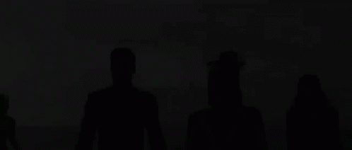a group of people standing in the shadows