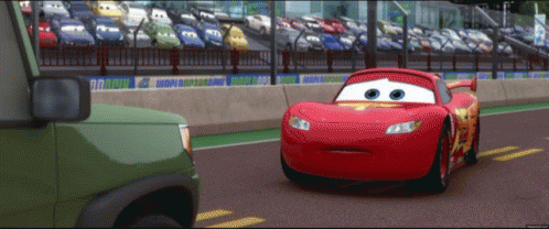 the character from cars drives down the road with cars in the background