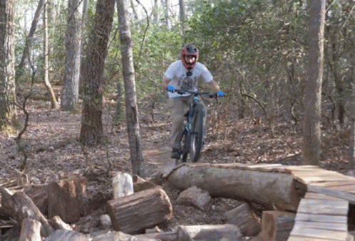 a man on a bike riding over a pile of wood