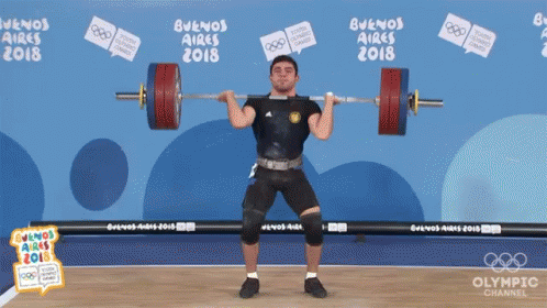 a man in shorts and a black top lifting a barbell
