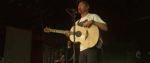 a man playing an acoustic guitar in front of microphones