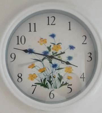 a clock with flowers painted on it is hanging on a wall