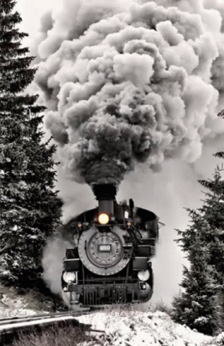 an old train with smoke coming from it traveling through the snow