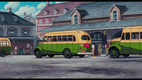 two old busses are parked near a crowd