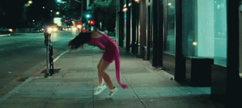 woman in a purple outfit dancing on a sidewalk