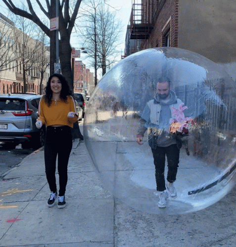 the woman is walking beside a guy inside a bubble