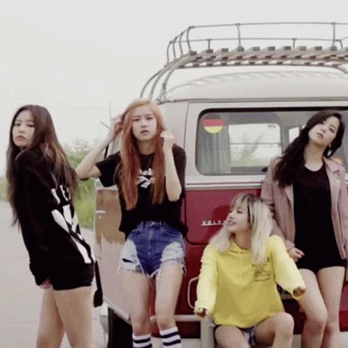 group of girls sit and stand by the back of a van