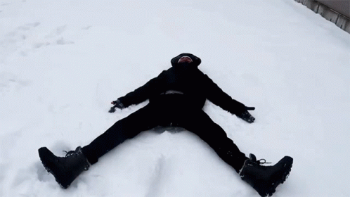 a man laying on the ground while snowboarding