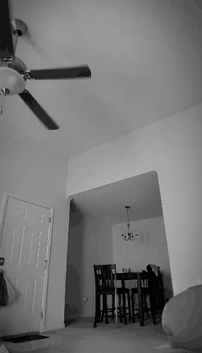 an empty room that has a ceiling fan and a small table in it