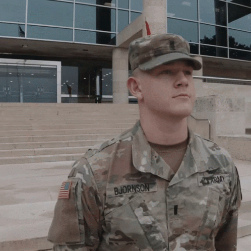 a soldier in uniform standing in front of a building