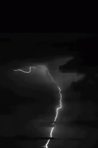 lightning striking on a dark night over a lake