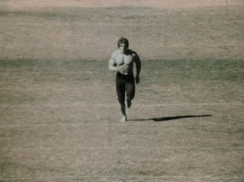 a man runs on a beach in an athletic outfit