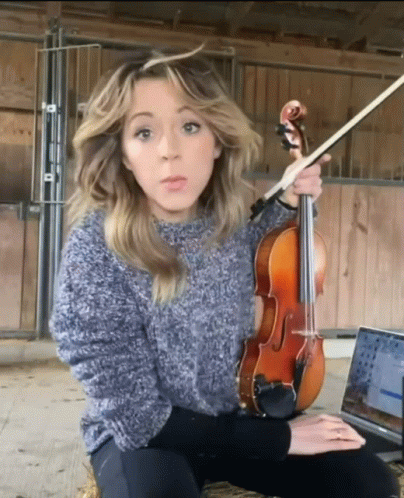 a lady sitting and playing her violin with both hands