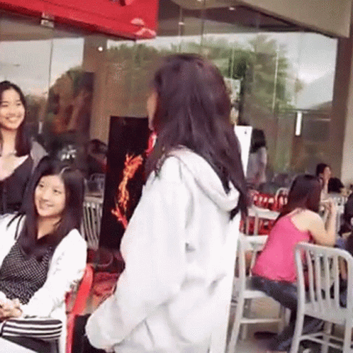an asian woman is talking to another asian lady who is wearing a black and white top