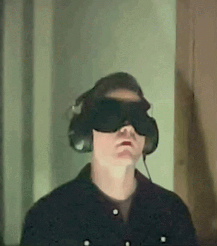 a man in a dark room wearing a mask with a television underneath him