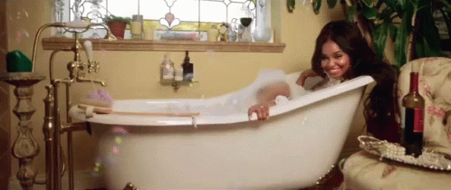 a woman sitting inside a bathtub while holding onto the tub