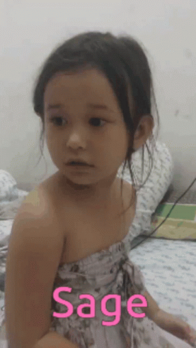 a little girl with blue skin sitting on a bed