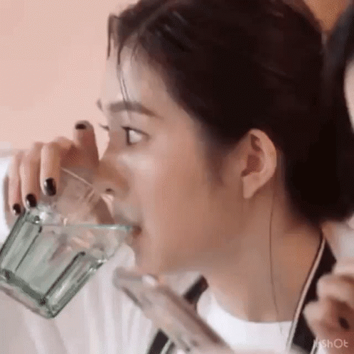 a woman in white shirt drinking from a blender