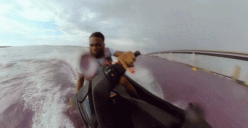man riding jet ski down a hill surrounded by clouds