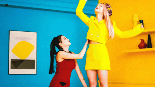 two s wearing colorful clothing, each reaching up to drink from plastic cups