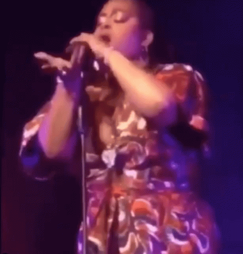 a woman in colorful dress with a microphone on stage