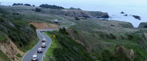 cars are lined up along a cliff side on a road