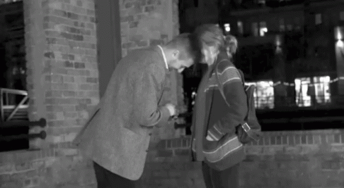 a man and woman talking on the sidewalk of a building