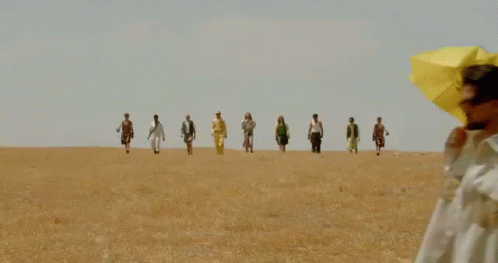 group of people walking across blue grass in the desert