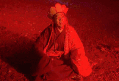 a man with blue light on his face sitting on ground