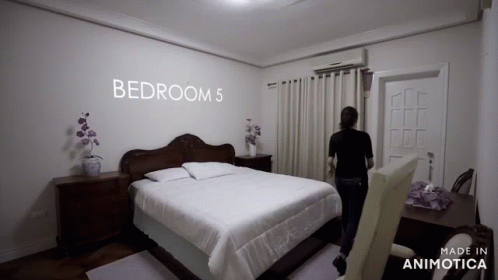 the woman is standing in her bedroom looking at the bed
