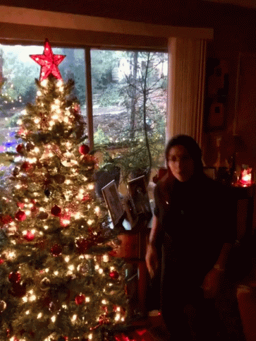a woman posing in front of a christmas tree