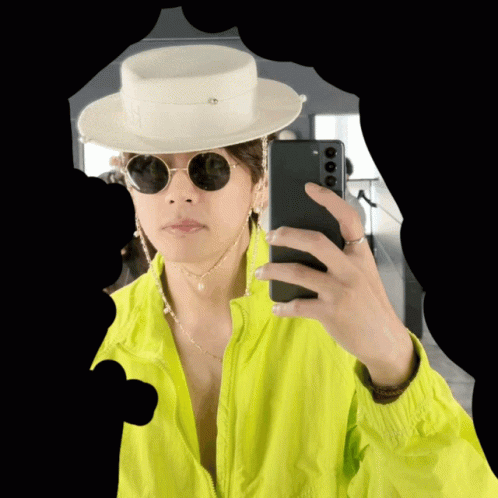 a person with glasses and a hat holding a cell phone