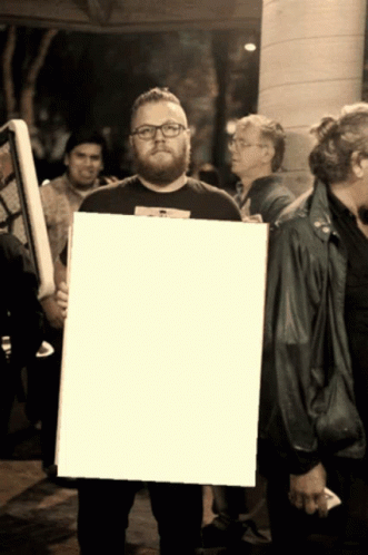 black and white pograph of man holding up a large white sign