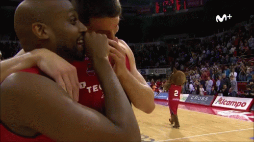 an athlete hugging another player in front of a crowd