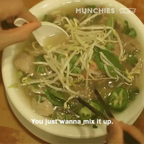 a person stirring up some noodles in a bowl