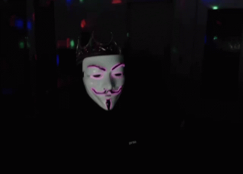 a man with a guy with a guy mask on in a dark room