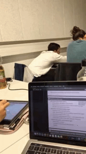 two men in the background are looking at an open laptop