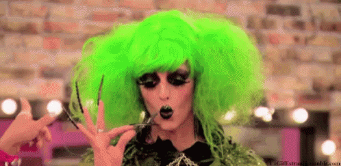 a woman with bright green hair and makeup is making a hand sign